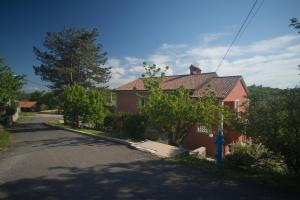 ein rotes Haus mit einem blauen Hydranten auf einer Straße in der Unterkunft Apartment Galjanić in Buzdohanj