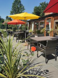 een patio met tafels en stoelen met parasols bij Hotel Bal in Tournehem
