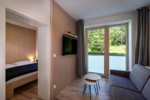 1 dormitorio con cama, sofá y ventana en TATRYSTAY Bernard Apartments, en Nový Smokovec