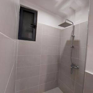 uma casa de banho com um chuveiro e uma televisão na parede em Rondine Studio Apartment em Tirana