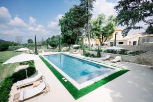 a swimming pool with two chairs and an umbrella at Le Domaine du Fortin in Ménerbes
