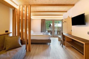 a hotel room with a bed and a desk and a tv at Agriturismo Bosco d'oro 4 in Livigno