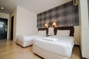 two white beds in a room with a wall at De' Garden Hotel, Butterworth in Butterworth