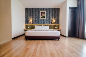 a bedroom with a bed and two tables with lamps at De' Garden Hotel, Butterworth in Butterworth