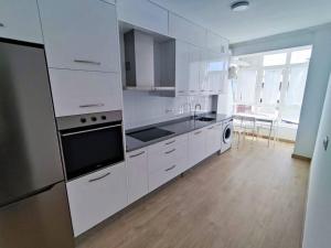 a kitchen with white cabinets and stainless steel appliances at Mariña Home in Ourense