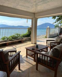 un porche con mesas y sillas y vistas al océano en EVIA DREAM FAMILY APARTMENTS, en Edipsos