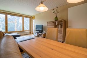 een woonkamer met een tafel en een televisie bij Viktoria B33, Wohnung mit herrlicher Aussicht in Arosa