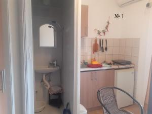 uma pequena cozinha com um lavatório e uma cadeira em OLGA apartmani em Sutomore
