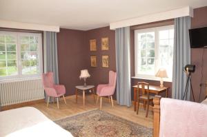 1 dormitorio con sillas rosas, mesa y cama en Moulin de la Cuse - Chambre La Cuse, en Cusance