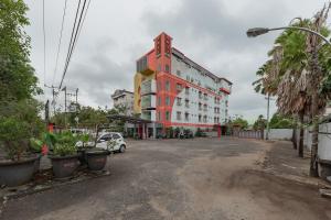 ein rot-weißes Gebäude mit einem Auto, das vorne geparkt ist in der Unterkunft Urbanview Hotel Onyx Ketapang by RedDoorz in Ketapang