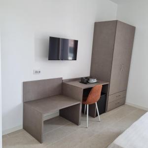 Habitación con escritorio, silla y TV. en Corte Bottura agriturismo, en Castelnuovo del Garda