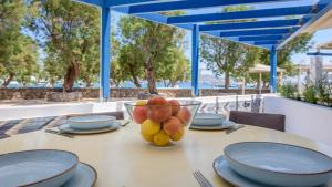 a table with plates and a bowl of fruit on it at Armenakishouses in Pollonia