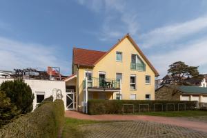 a large yellow house with a balcony on a street at Ostseeallee 32b Ostseeallee 32b 1-1 in Kühlungsborn