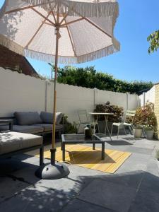 a patio with an umbrella and a table and a couch at Guesthouse Poppies in Ostend