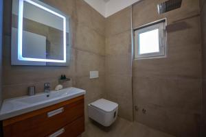 a bathroom with a toilet and a sink and a window at Inada Rooms Ksamil in Ksamil