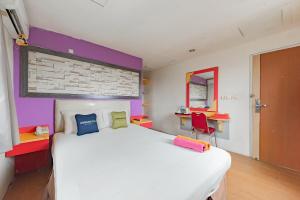 Un dormitorio con una gran cama blanca y una silla roja. en Urbanview Hotel Onyx Ketapang by RedDoorz, en Ketapang