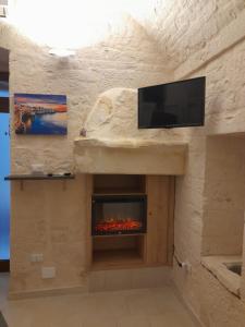 d'un mur en pierre avec une cheminée et une télévision. dans l'établissement Casa Micaela, à Noci