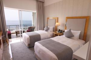 a hotel room with two beds and a balcony at Riviera Hotel and Beach Lounge, Beirut in Beirut
