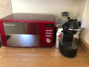 a red microwave sitting on top of a wooden floor at Laundry Cottage in Dumfries +24 photos