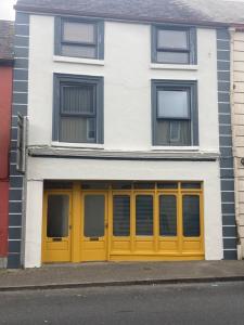 a white building with yellow doors and windows at Kilaturley house apartment in Swinford