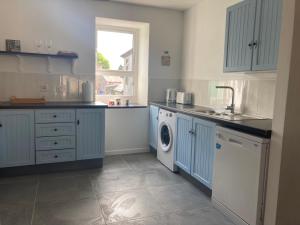 a kitchen with blue cabinets and a washing machine at Kilaturley house apartment in Swinford
