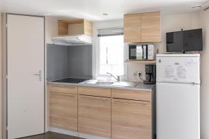 a small kitchen with a refrigerator and a sink at Camping 3* Les Templiers in Roquebillière
