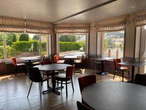 restauracja ze stołami, krzesłami i oknami w obiekcie Hotel Restaurant Le Phare w mieście Perros-Guirec