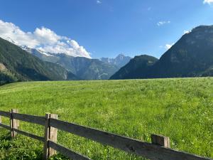 Ein Zaun auf einem Feld mit Bergen im Hintergrund in der Unterkunft Loft in the Alps Penthouse in Schwendau