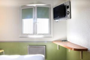 a room with a bed and a tv and a window at Hotel Inn Design Issoudun in Issoudun