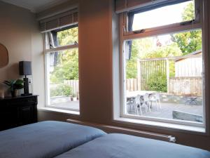 een slaapkamer met een bed en een raam met een patio bij ‘t Wirdummer Hof - family-friendly guesthouse in Wirdum