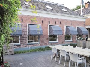 un bâtiment en briques avec des auvents gris, des tables et des chaises dans l'établissement ‘t Wirdummer Hof - family-friendly guesthouse, à Wirdum