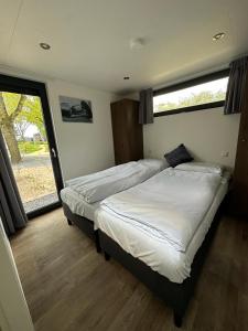 2 camas individuales en un dormitorio con ventana en Traum Ferienhaus mit Dachterrasse am Veluwemeer, en Hulshorst