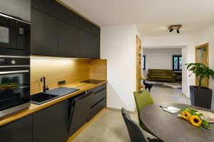 a kitchen with black cabinets and a table with flowers on it at Guest House Žerjal in Podnanos