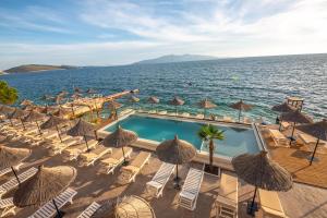 una piscina con sillas y sombrillas junto al océano en Hotel Jaroal, en Sarandë