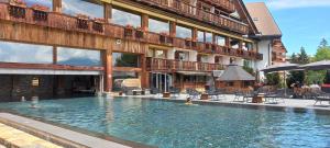 a large swimming pool in front of a building at Apartment 24 Hotel Etrier pool & spa in Crans-Montana