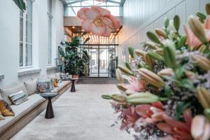 a hallway with couches and flowers in a building at Botanic Sanctuary Antwerp - The Leading Hotels of the World in Antwerp