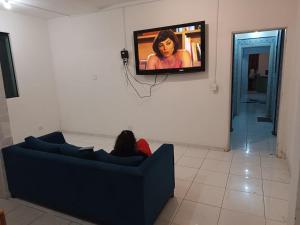 una persona sdraiata su un divano in una stanza con televisore di Mansão Akkui Hostel a San Paolo