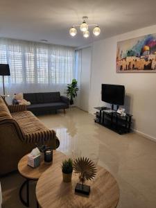 a living room with a couch and a tv at Краткосрочная посуточная аренда Бат-Ям! in Bat Yam