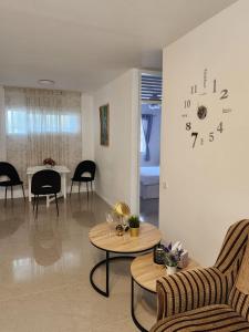 a living room with a table and a clock on the wall at Краткосрочная посуточная аренда Бат-Ям! in Bat Yam