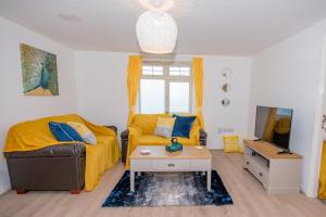 een woonkamer met een bank en een tv bij KVM - Sunshine Apartment by KVM Stays in Peterborough