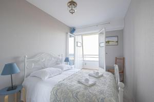 ein weißes Schlafzimmer mit einem Bett mit zwei Handtüchern darauf in der Unterkunft Les Marinas in Courseulles-sur-Mer