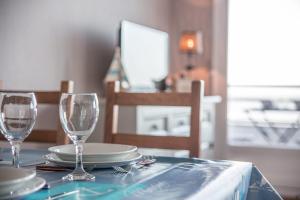 a table with two wine glasses and plates on it at Les Marinas front of the beach in Courseulles-sur-Mer