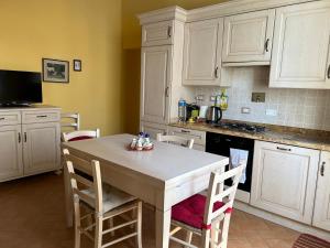 a kitchen with white cabinets and a table with chairs at A Casa di Marzia in Rapolano Terme