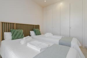 two beds in a room with white and green pillows at Jardinana - apartment with two bedrooms close to beach and town center in La Cala de Mijas +29 photos