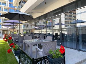 an outdoor patio with tables and chairs and umbrellas at Hotel Javu in Mamaia Sat/Năvodari