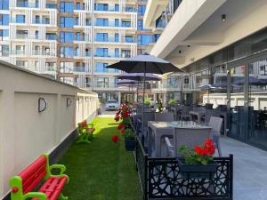 an outdoor patio with tables and chairs and an umbrella at Hotel Javu in Mamaia Nord