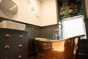 a bathroom with a tub and a sink and a mirror at Cosy Village House in Waddington