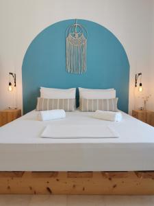 a bedroom with a large white bed with a blue wall at KR Apartments in Aliki