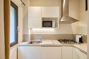 a white kitchen with a sink and a microwave at Residenza Stuart - Blanche Stuart studio - Dimora storica in Montepulciano