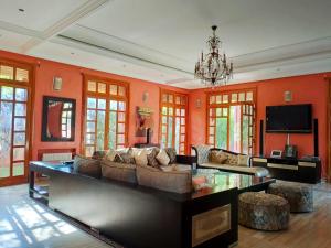 ein großes Wohnzimmer mit orangefarbenen Wänden und einem Sofa in der Unterkunft Villa Apricot - Golf Amelkis in Marrakesch